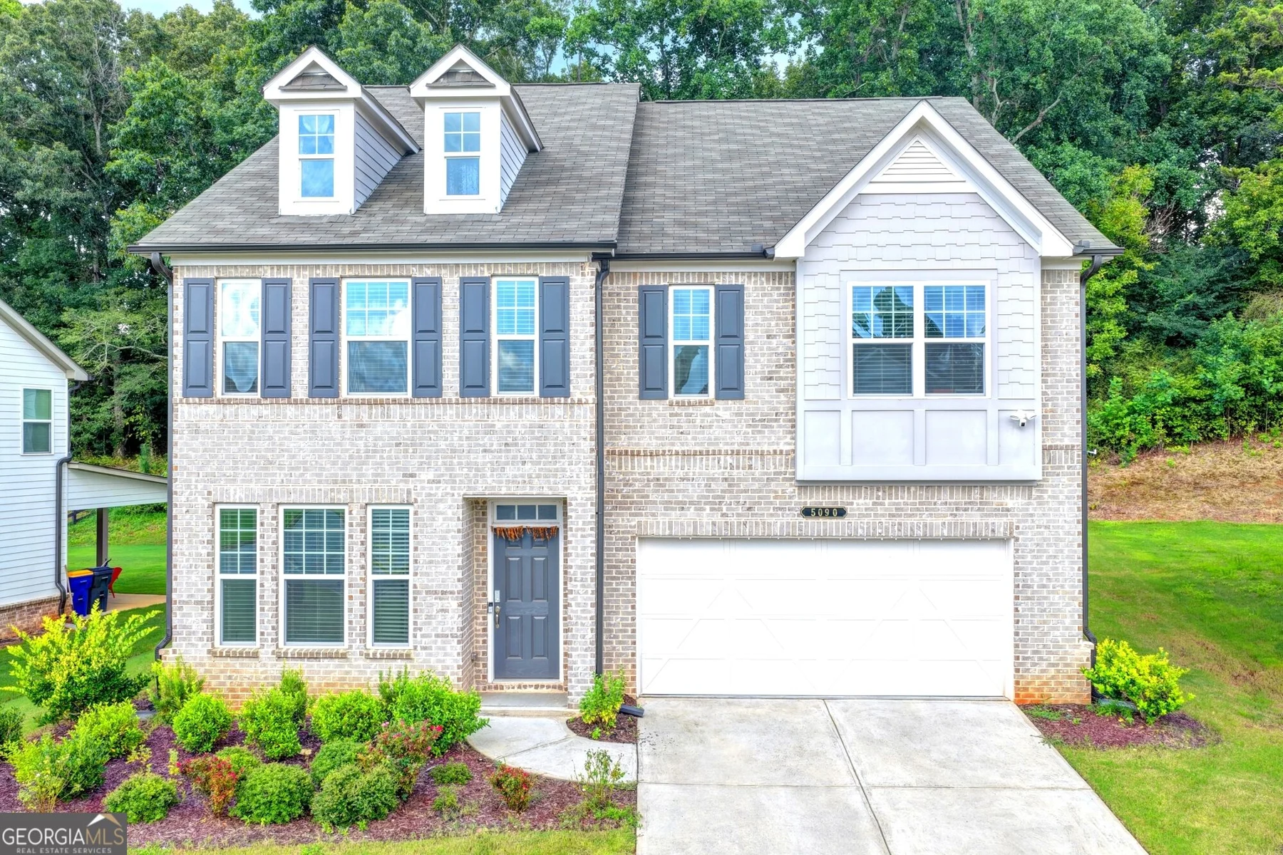Front exterior with brick facade, covered entry and two-car garage