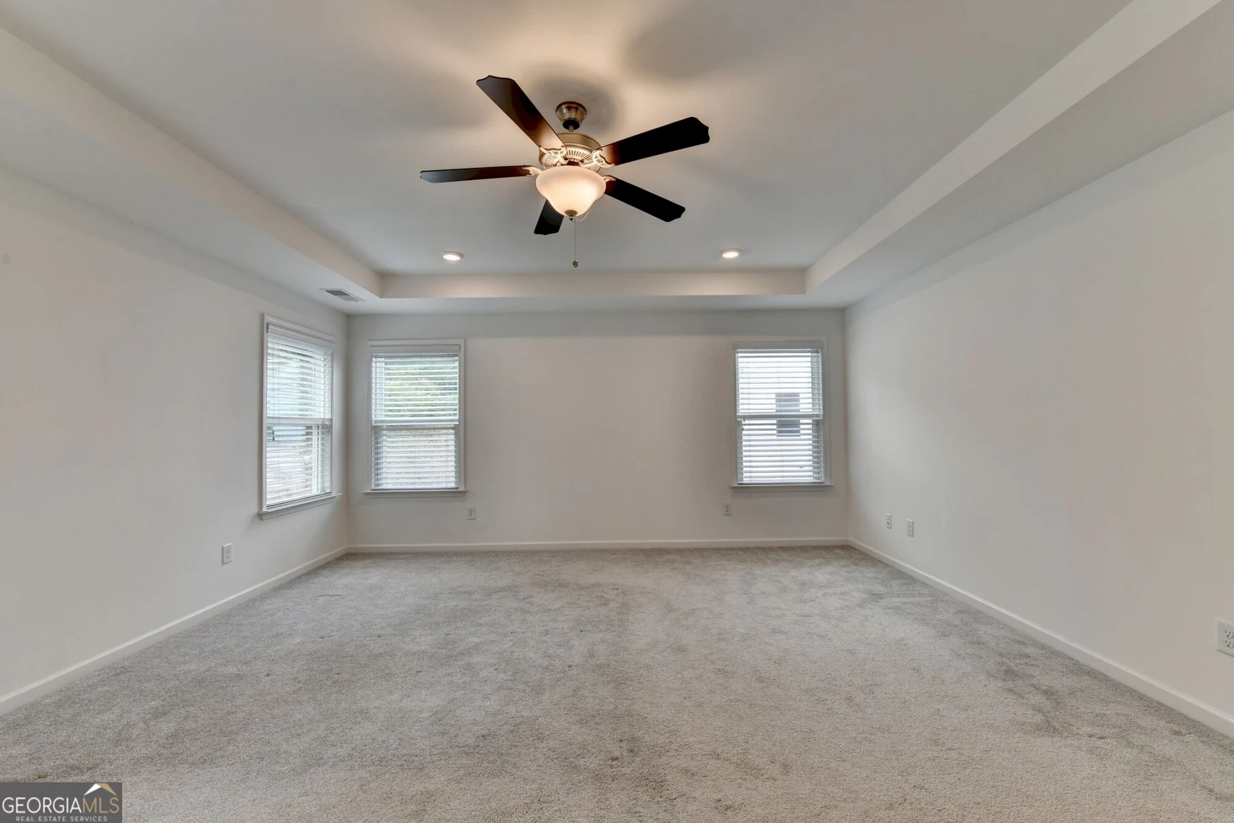 Primary bedroom with tray ceiling and ceiling fan